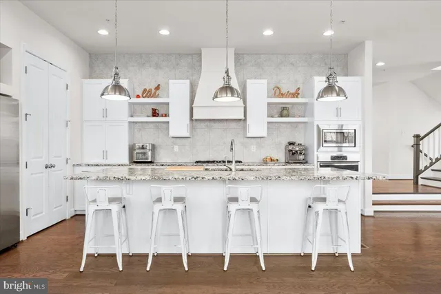 a large kitchen with granite countertop lots of white cabinets and stainless steel appliances