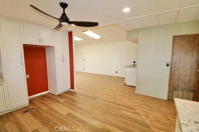 a view of empty room with wooden floor and fan