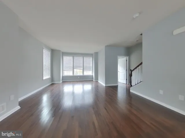 a view of an empty room with wooden floor and window