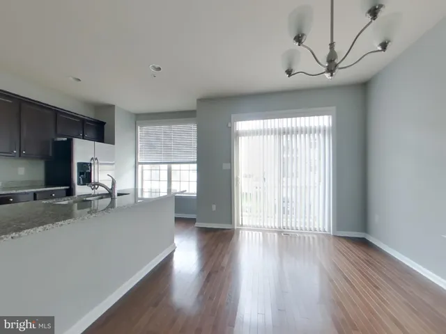 a kitchen with stainless steel appliances granite countertop a stove a sink a refrigerator white cabinets and wooden floor