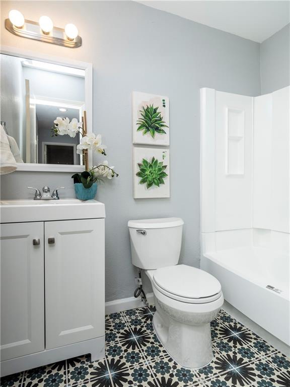 7004 Circle S Road, Unit B Austin, TX 78745 - Photo 11 of 12 Bold patterned tile flooring anchors this well-appointed, compact bathroom featuring a vanity and shower.