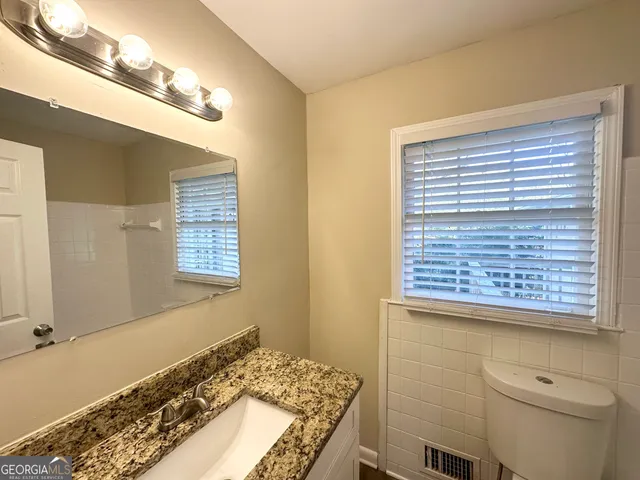 a bathroom with a granite countertop sink and a toilet