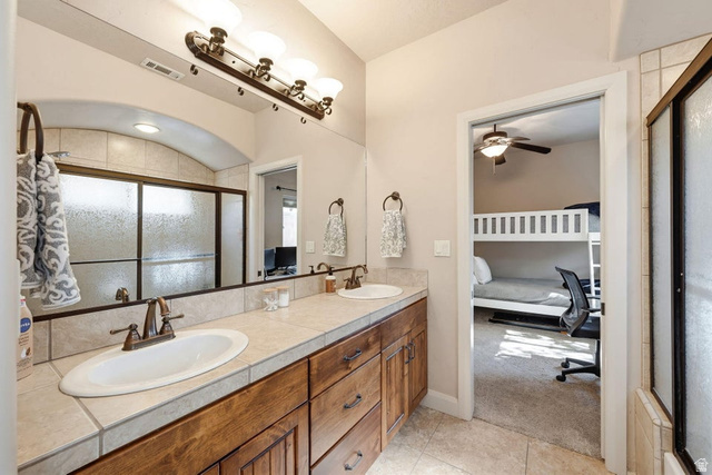 1609 East 10 S Street St. George, UT 84790 - Photo 39 of 68 Bathroom vanity featuring dual undermount sinks, bronze finish faucets, and a tiled countertop