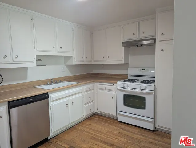 a kitchen with granite countertop white cabinets and white appliances