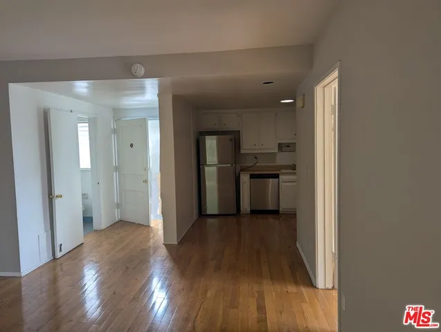 a view of a kitchen with wooden floor a sink and stainless steel appliances