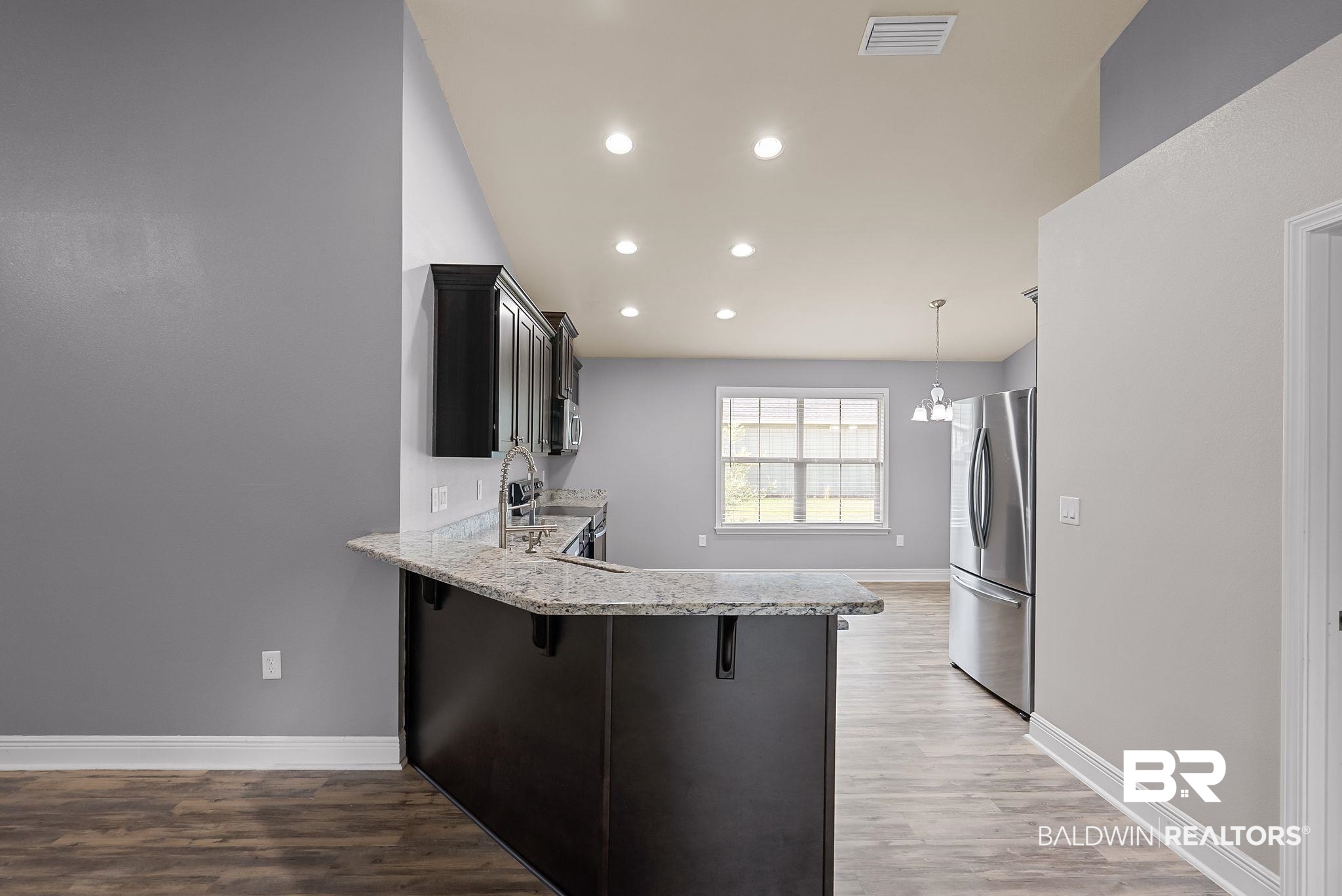 22076 Garland Loop Silverhill, AL 36576 - Photo 6 of 27 Kitchen featuring a breakfast bar with stone-finish countertop, dark wood cabinetry, recessed lighting, and stainless steel appliances