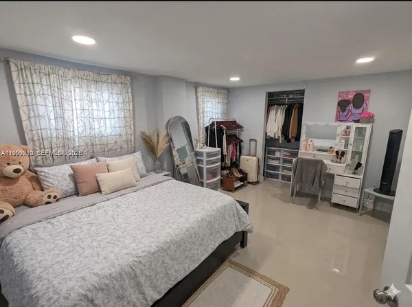 a bedroom with a bed a desk and large windows