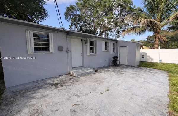 a backyard of a house with wooden fence and a tree