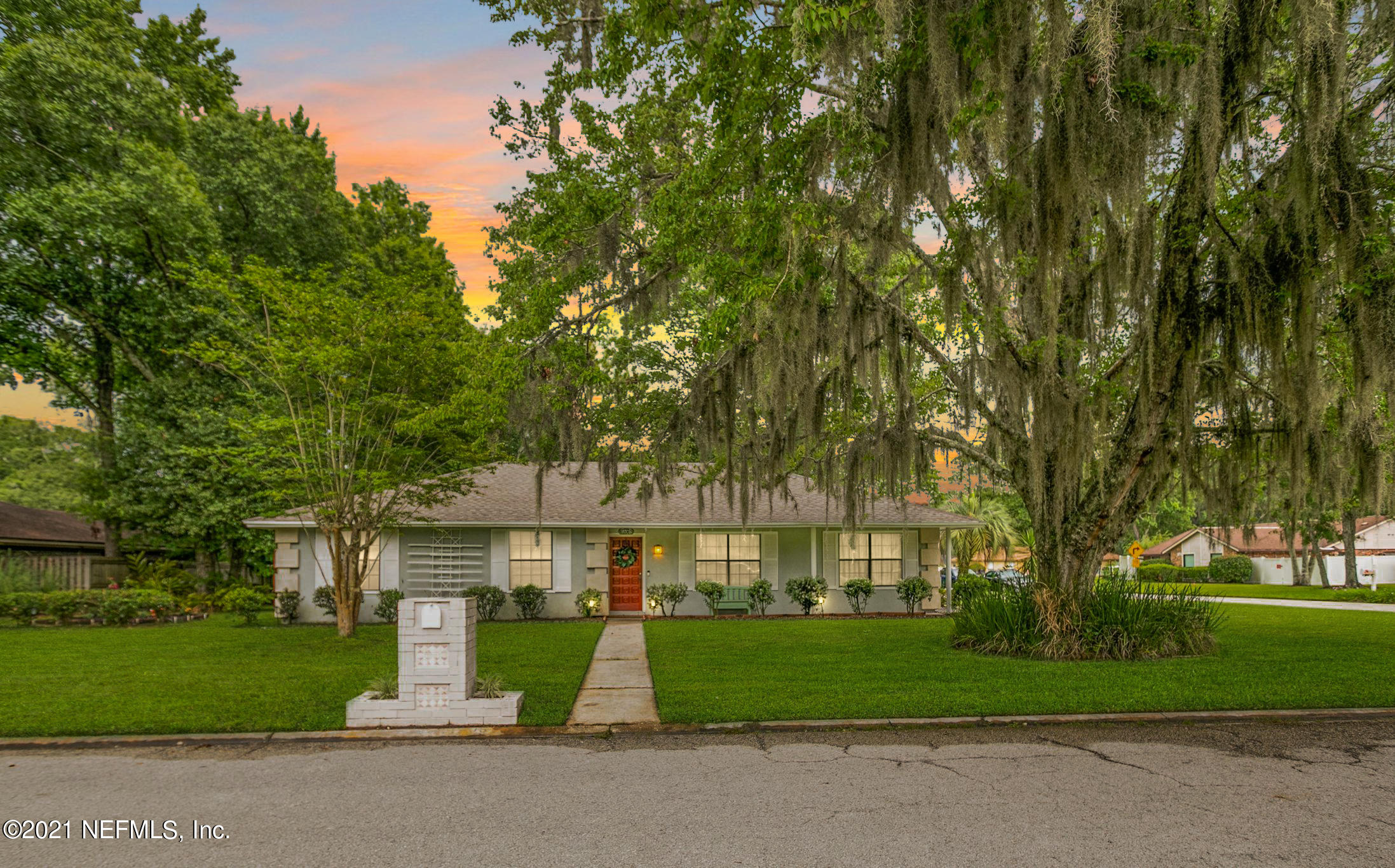 a front view of a house with a garden and trees