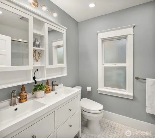 a bathroom with a toilet a sink a vanity a window and mirror