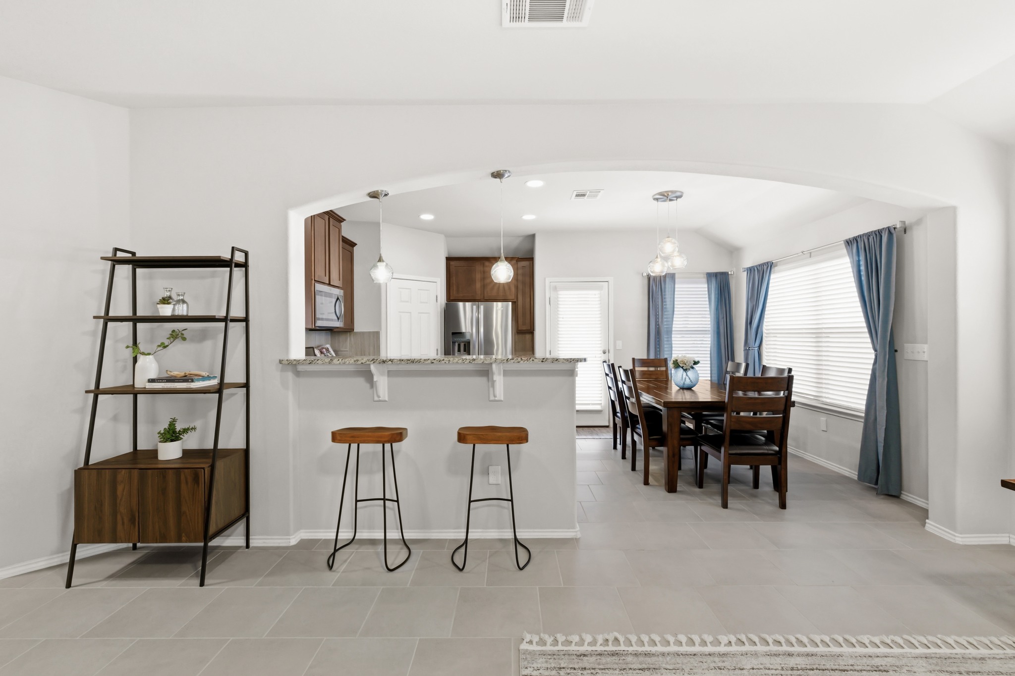 219 Noddy Road Buda, TX 78610 - Photo 13 of 31 Kitchen with arched walkways, a breakfast bar area, light stone counters, a peninsula, and stainless steel appliances