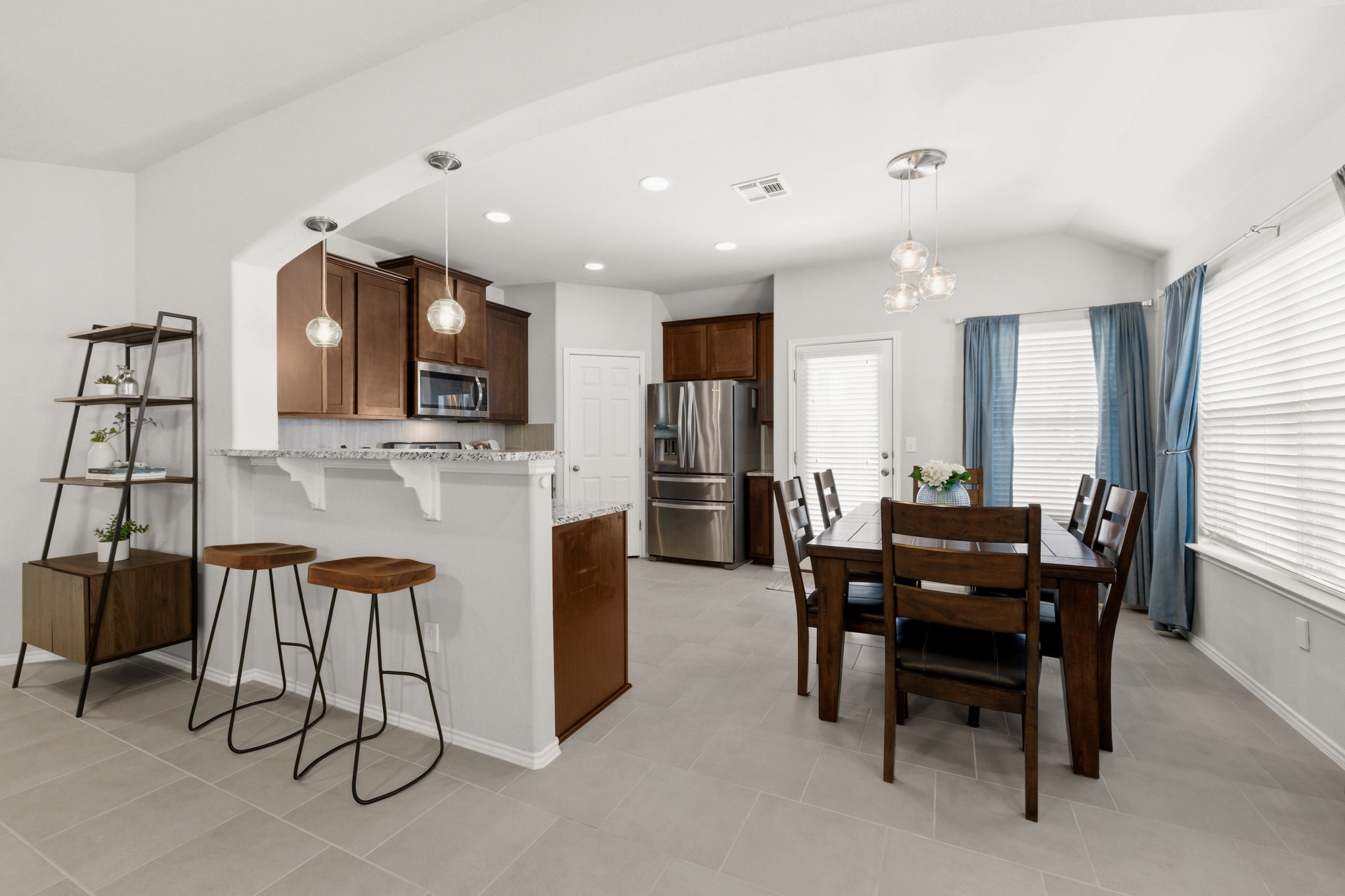 219 Noddy Road Buda, TX 78610 - Photo 14 of 31 Kitchen featuring a kitchen bar, a peninsula, stainless steel appliances, light stone countertops, and hanging lights