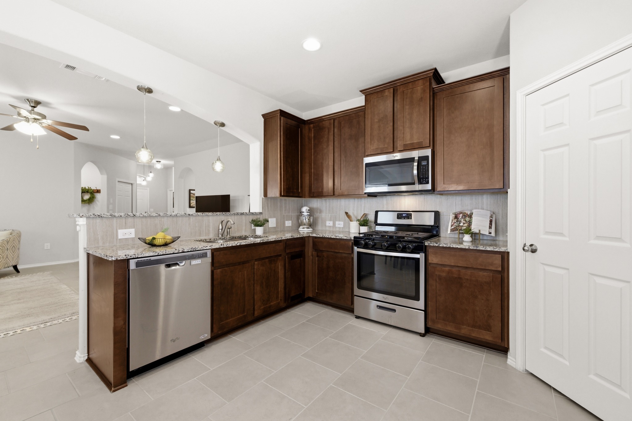 219 Noddy Road Buda, TX 78610 - Photo 15 of 31 Kitchen with stainless steel appliances, backsplash, light stone counters, dark wood finish cabinets, and a peninsula