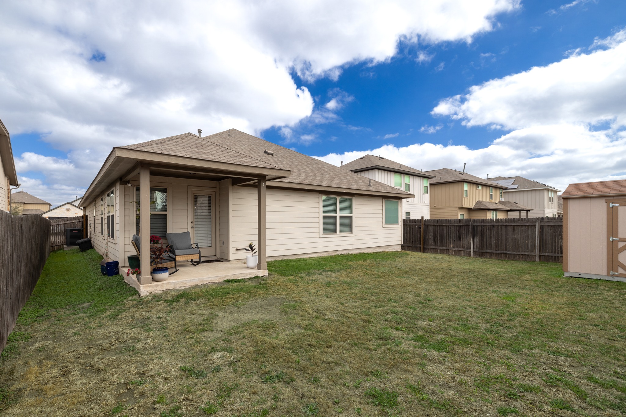 219 Noddy Road Buda, TX 78610 - Photo 29 of 31 Back of property with a storage shed, a patio, a fenced backyard, and roof with shingles