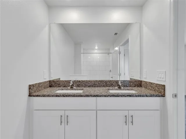 a bathroom with a granite countertop sink and a mirror