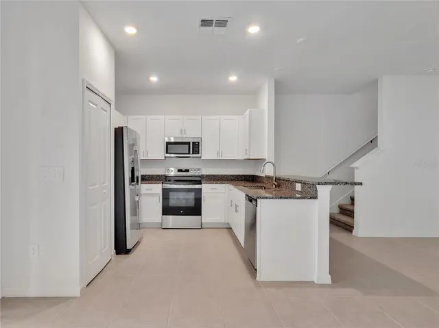 a kitchen with a sink stainless steel appliances and white cabinets