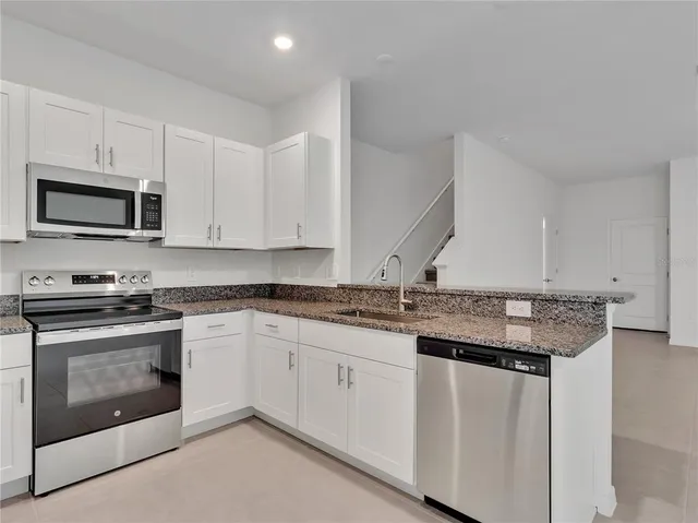 a kitchen with granite countertop a stove sink and microwave