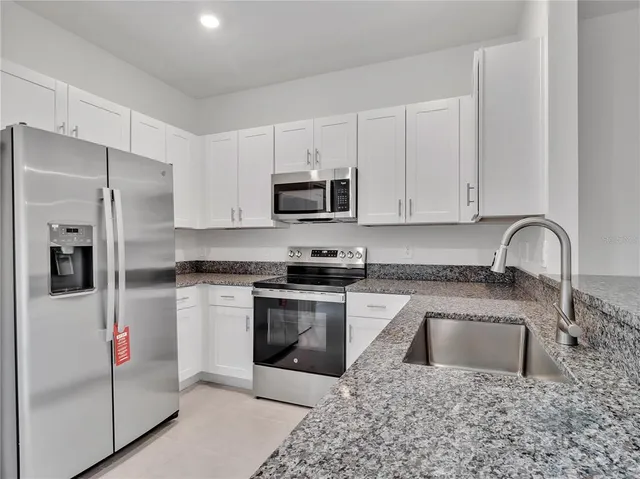 a kitchen with granite countertop a stove sink and refrigerator