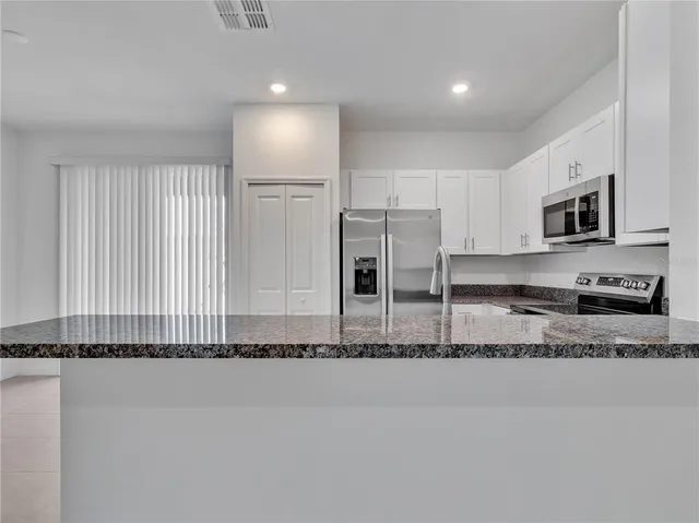 a kitchen with stainless steel appliances granite countertop a stove a sink and a refrigerator