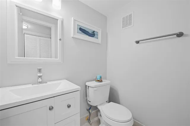 a bathroom with a toilet sink vanity and mirror