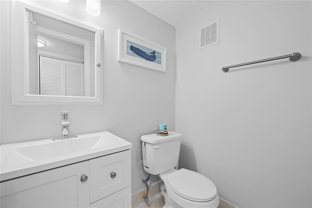 318 Oakridge R, Unit 318 Deerfield Beach, FL 33442 - Photo 12 of 26 a bathroom with a toilet sink vanity and mirror