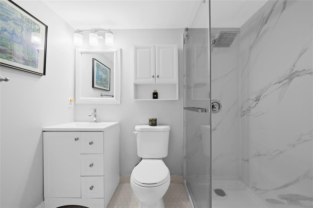 318 Oakridge R, Unit 318 Deerfield Beach, FL 33442 - Photo 16 of 26 a bathroom with a toilet a sink a mirror and vanity