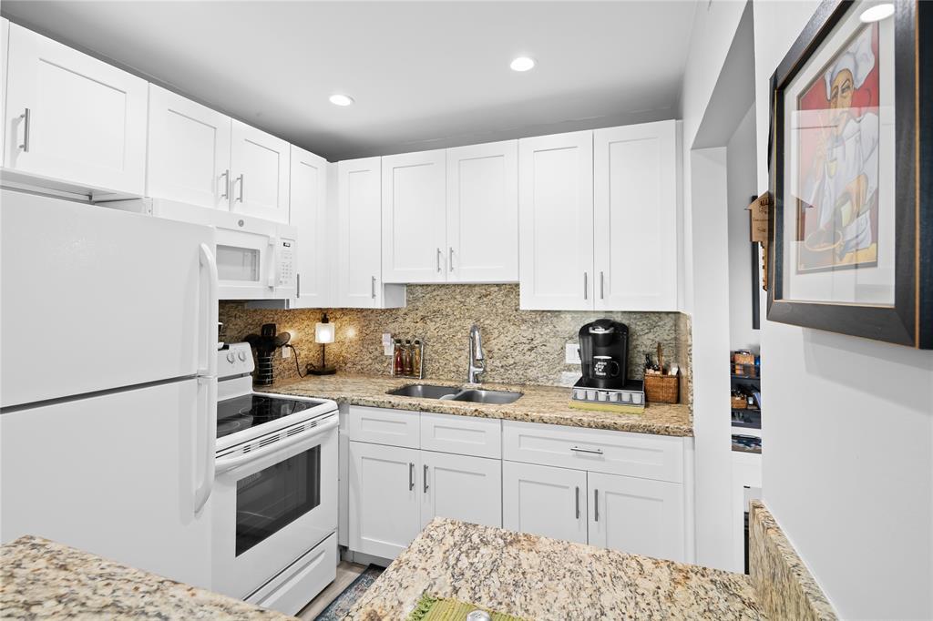 318 Oakridge R, Unit 318 Deerfield Beach, FL 33442 - Photo 9 of 26 a kitchen with stainless steel appliances granite countertop a stove a sink and a refrigerator