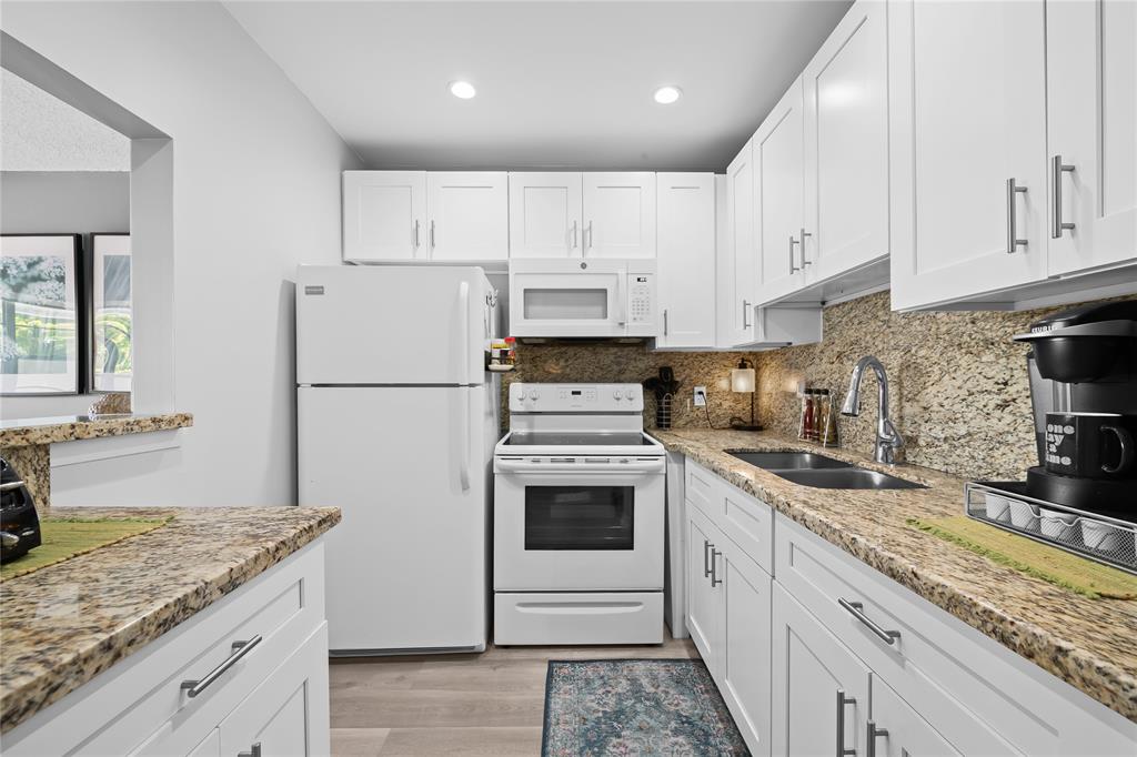 318 Oakridge R, Unit 318 Deerfield Beach, FL 33442 - Photo 10 of 26 a kitchen with granite countertop white cabinets and white stainless steel appliances