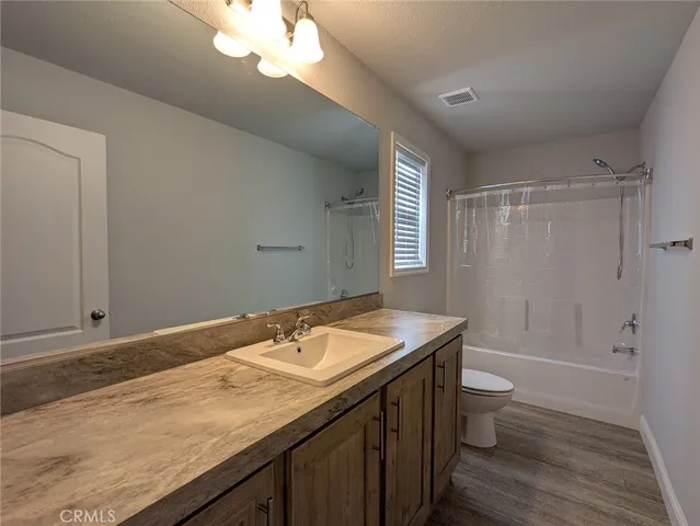 a bathroom with a granite countertop sink a toilet and shower