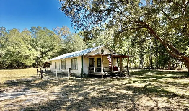 a view of a blue house with yard and sitting area