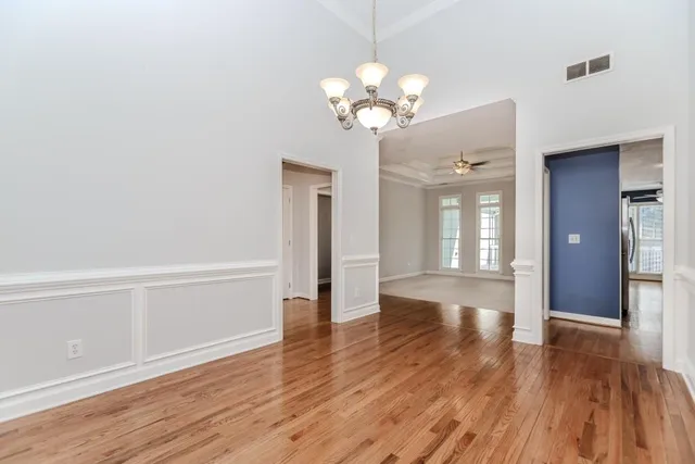 a view of an empty room with chandelier fan