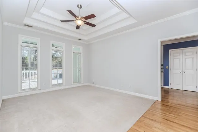 an empty room with chandelier fan and windows