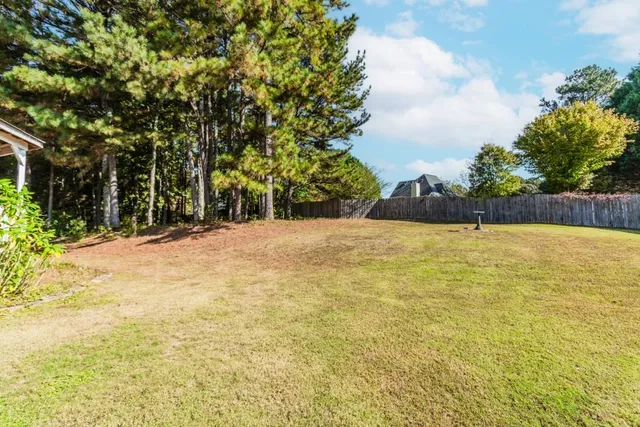 a view of an empty room with wooden floor fireplace and a window