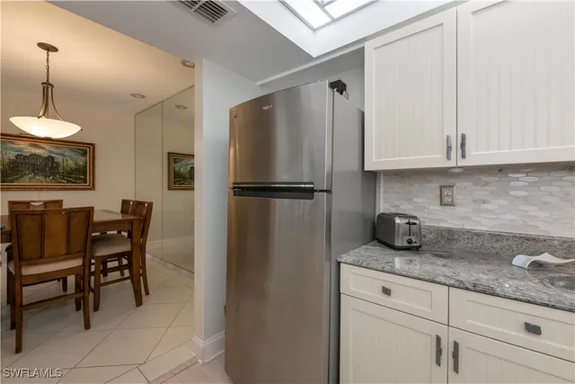 a kitchen with granite countertop a refrigerator a stove a dining table and chairs with wooden floor