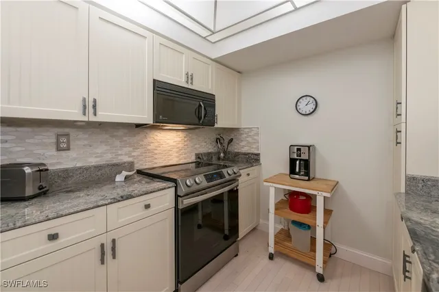 a kitchen with granite countertop a sink a stove and cabinets