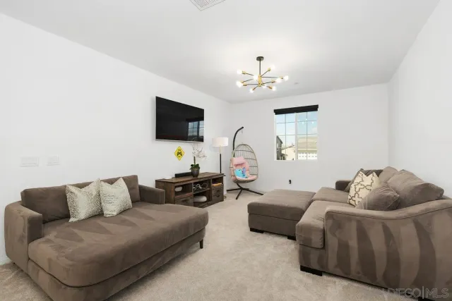 a living room with furniture a flat screen tv and a chandelier