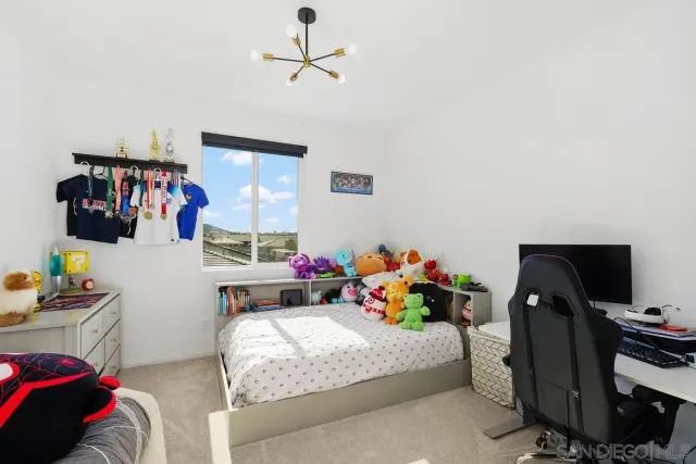 a bedroom with bed a computer on the desk and a couch