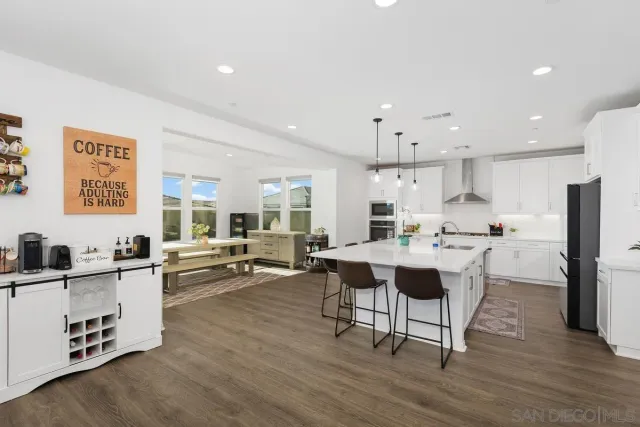 a living room with furniture a wooden floor and kitchen view