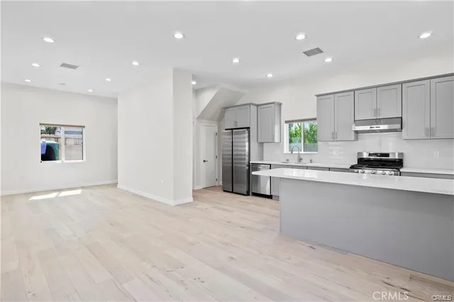 a large kitchen with stainless steel appliances granite countertop a large counter top a sink and a stove