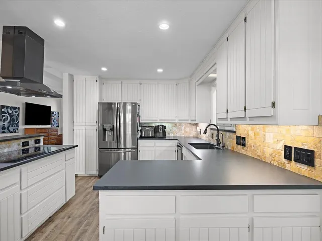 a kitchen with kitchen island granite countertop a sink a counter top space appliances and cabinets