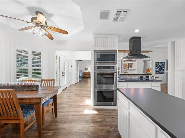 a kitchen with stainless steel appliances a dining table chairs and stove