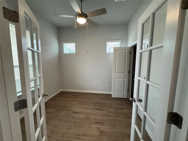 a view of an empty room with wooden floor and a window