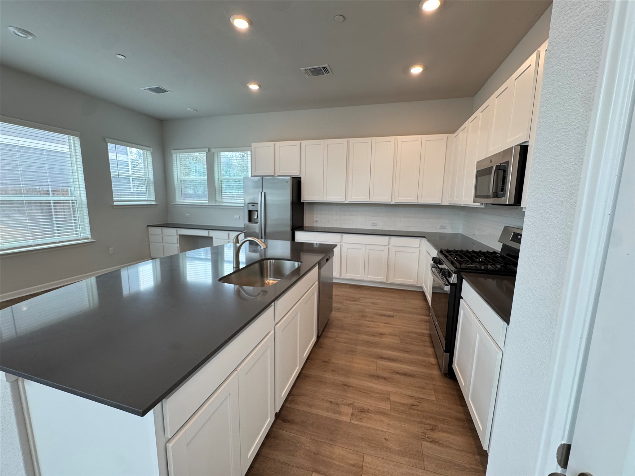 3000 Chisholm Trail Road, Unit 103 Round Rock, TX 78681 - Photo 8 of 32 Kitchen with a spacious island, stainless steel appliances, white cabinetry, recessed lighting, and dark wood finished floors