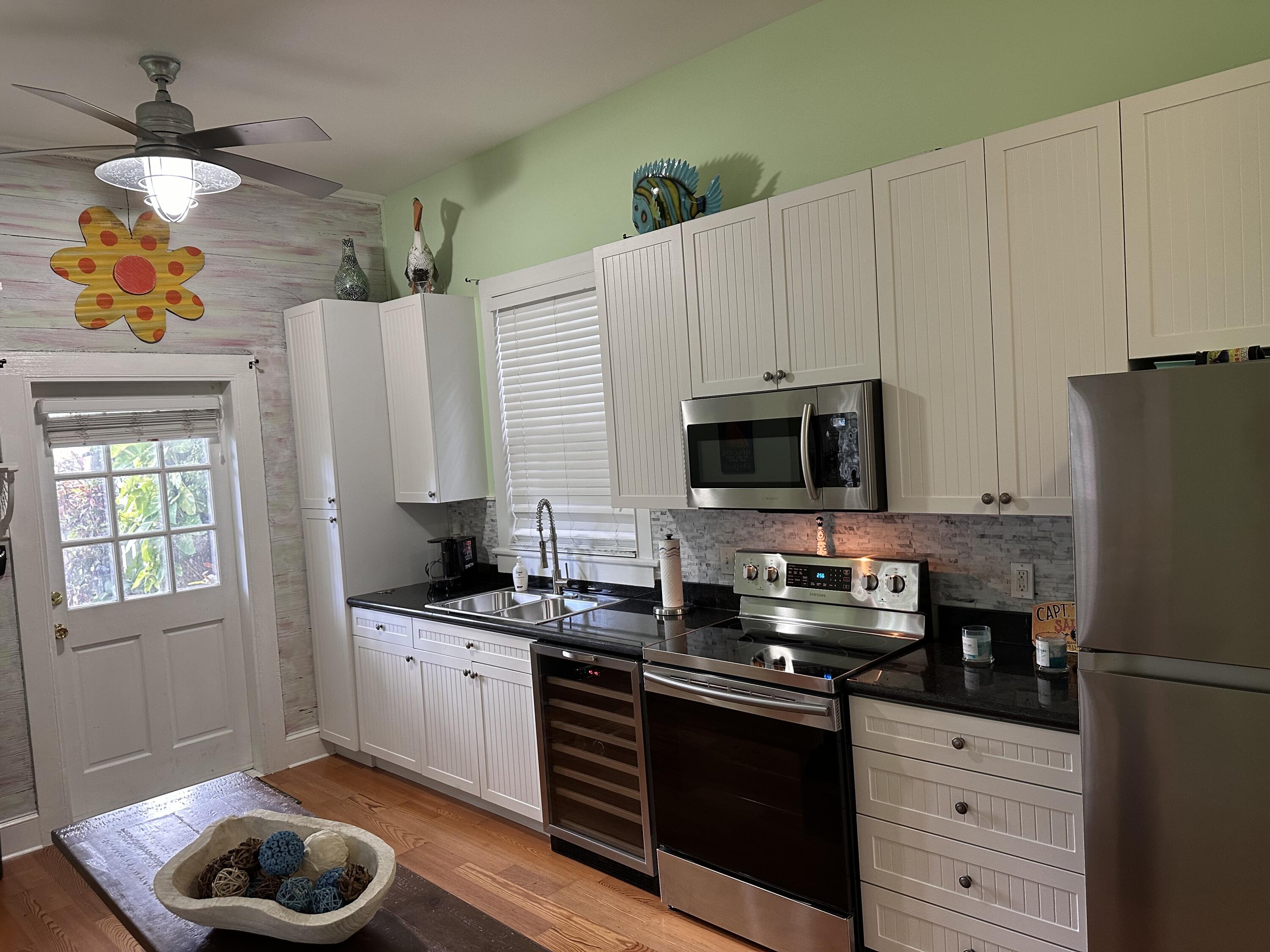 817 Eaton Street, Unit 1 Key West, FL 33040 - Photo 8 of 30 a kitchen with stainless steel appliances granite countertop a sink dishwasher a refrigerator and a stove with wooden floor