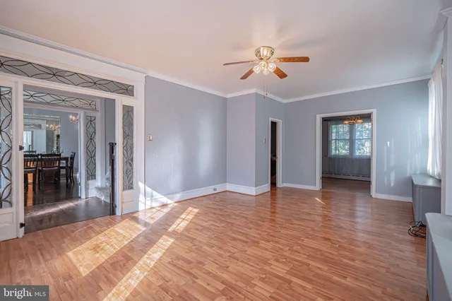 an empty room with wooden floor chandelier and window