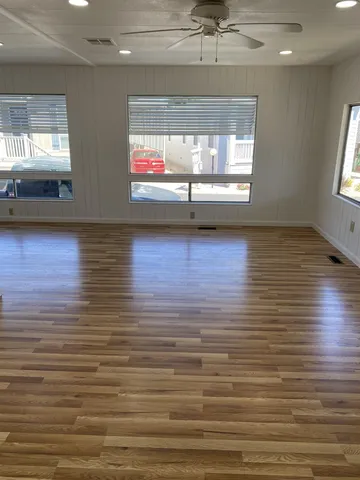 an empty room with wooden floor fireplace and windows