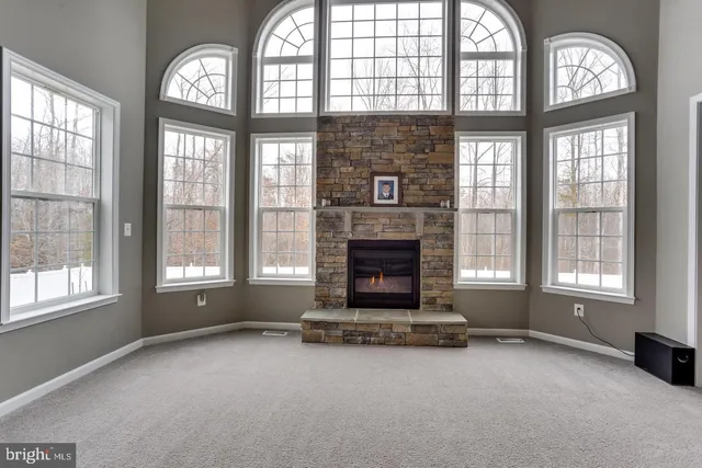 an empty room with a fireplace large windows and a fireplace