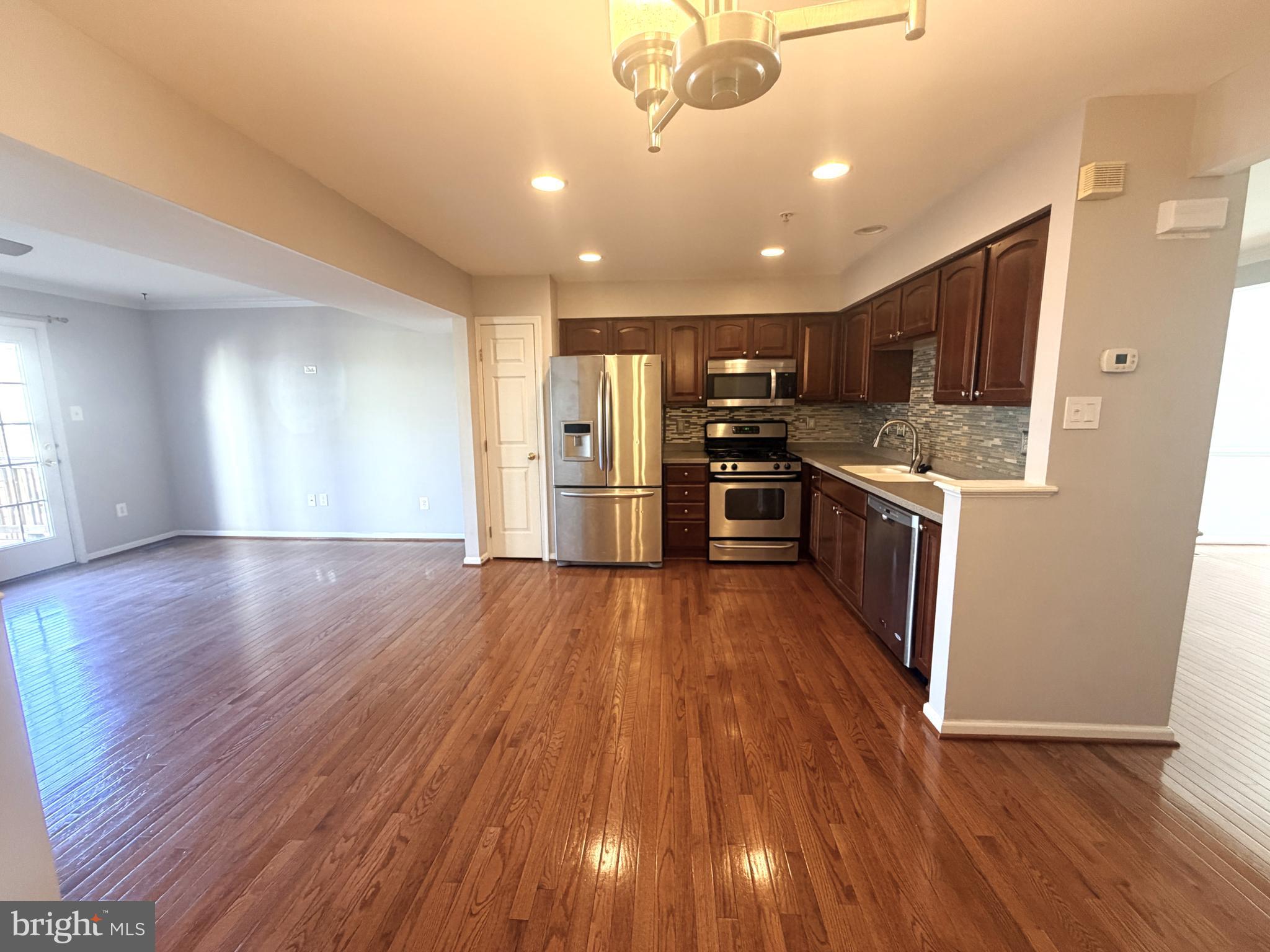 7088 Maiden Point Place, Unit 25 Elkridge, MD 21075 - Photo 7 of 29 a kitchen with stainless steel appliances granite countertop a stove top oven a refrigerator with wooden floors