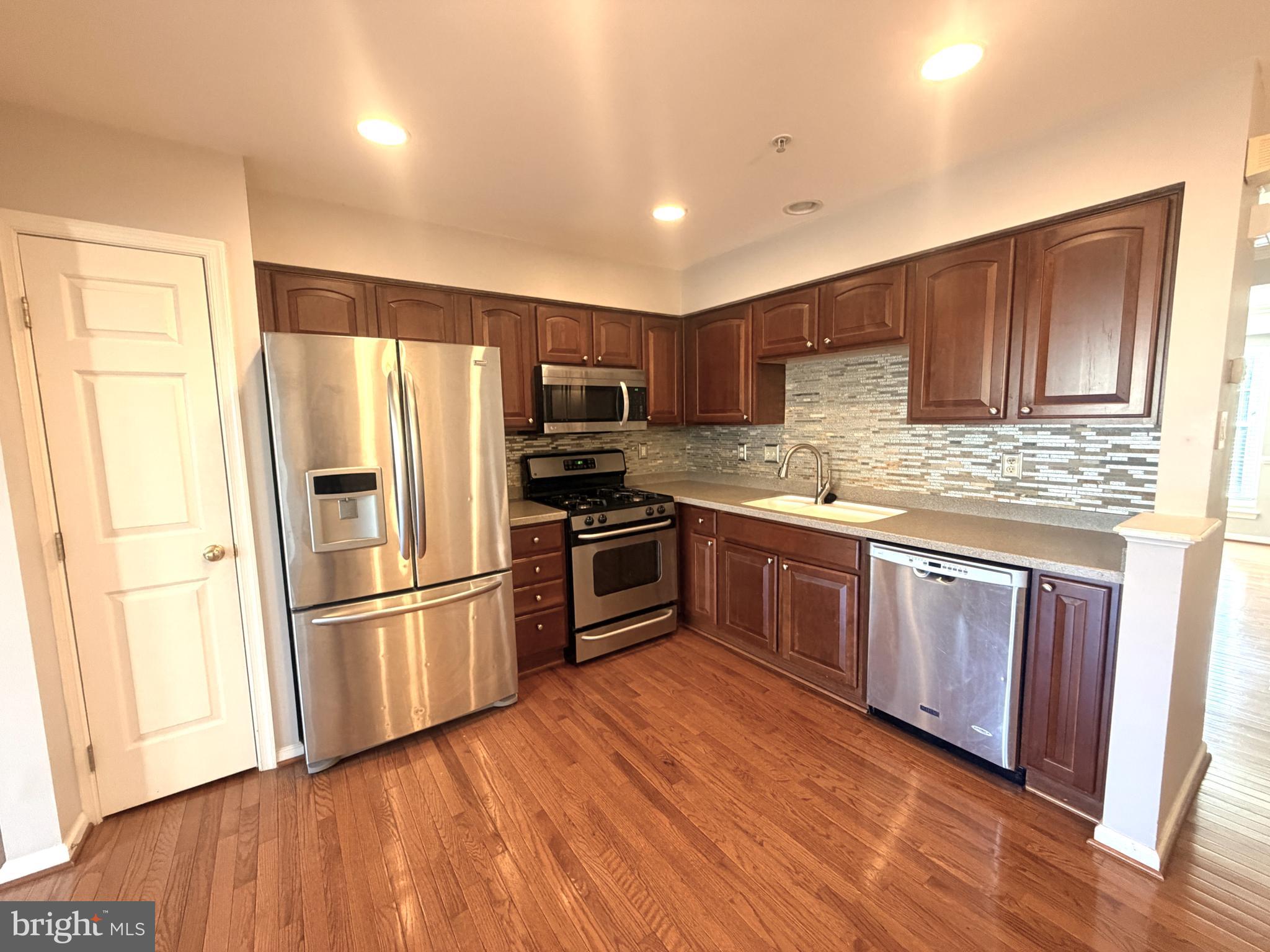 7088 Maiden Point Place, Unit 25 Elkridge, MD 21075 - Photo 8 of 29 a kitchen with granite countertop wooden floors stainless steel appliances and cabinets