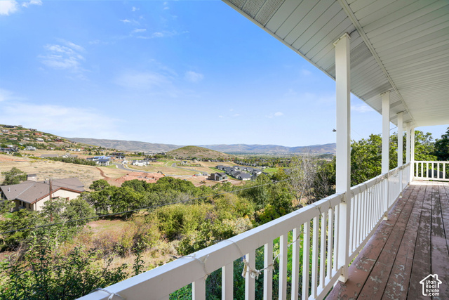 380 Luzern Road Midway, UT 84049 - Photo 22 of 41 Expansive covered deck with wood flooring and white railing, featuring distant mountain scenery and surrounding properties